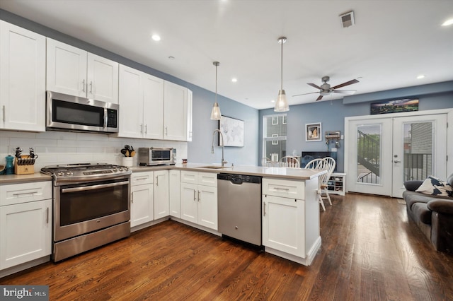 kitchen featuring kitchen peninsula, white cabinetry, hanging light fixtures, and appliances with stainless steel finishes