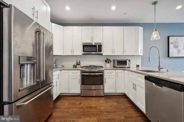 kitchen with hanging light fixtures, white cabinetry, sink, and appliances with stainless steel finishes