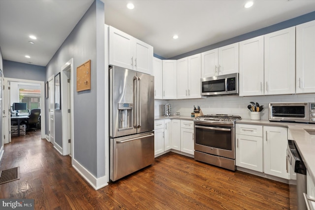 kitchen with white cabinets, appliances with stainless steel finishes, dark hardwood / wood-style flooring, and decorative backsplash