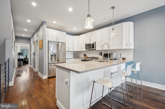 kitchen with kitchen peninsula, appliances with stainless steel finishes, tasteful backsplash, pendant lighting, and white cabinets