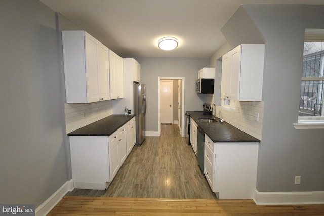 kitchen featuring appliances with stainless steel finishes, light hardwood / wood-style floors, sink, white cabinetry, and backsplash