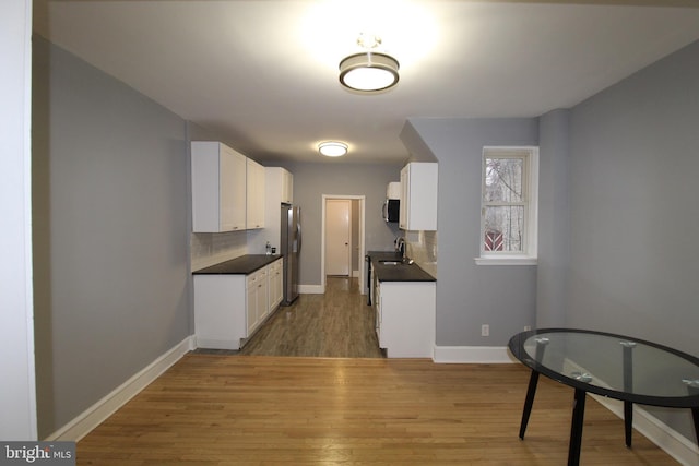 kitchen featuring sink, white cabinetry, light hardwood / wood-style floors, decorative backsplash, and appliances with stainless steel finishes