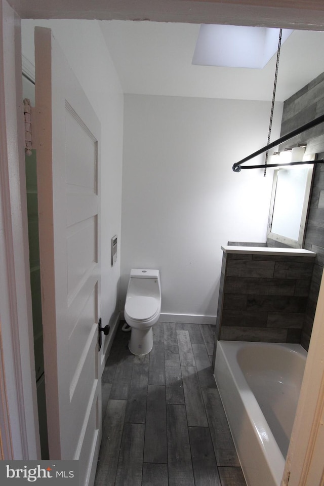 bathroom featuring toilet, a skylight, and a bathtub