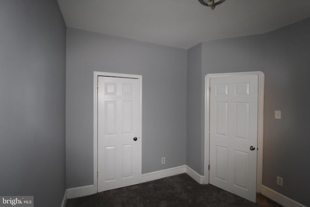 unfurnished bedroom with a closet and dark carpet