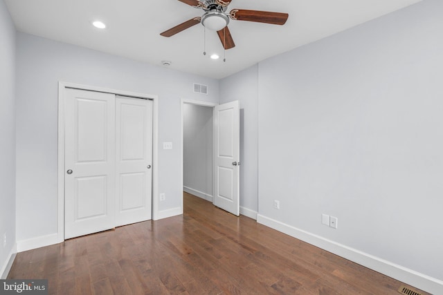 unfurnished bedroom featuring ceiling fan, a closet, and dark wood-type flooring