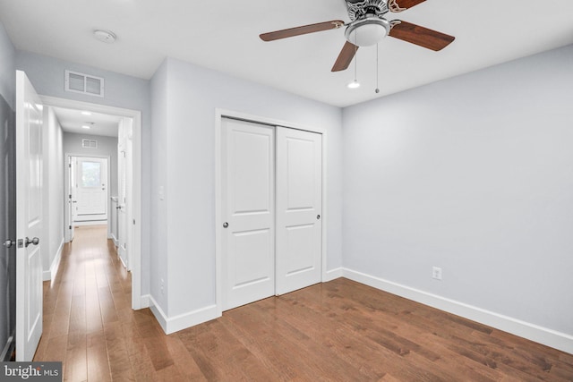 unfurnished bedroom featuring hardwood / wood-style flooring, ceiling fan, and a closet