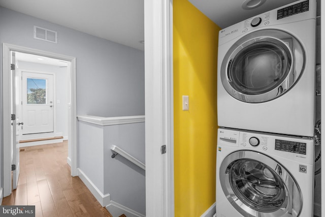 laundry area featuring hardwood / wood-style flooring and stacked washer / dryer