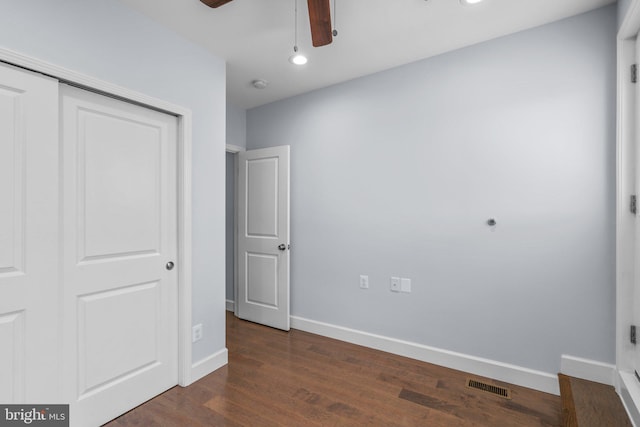 unfurnished bedroom with dark hardwood / wood-style flooring, ceiling fan, and a closet