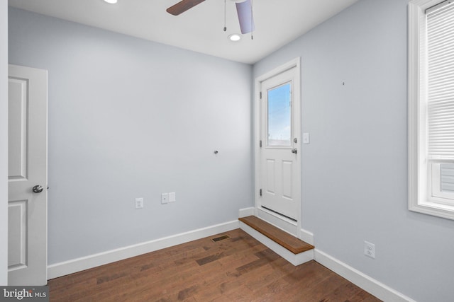 empty room featuring plenty of natural light, dark wood-type flooring, and ceiling fan