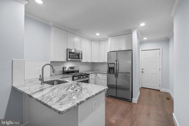 kitchen with sink, kitchen peninsula, light stone counters, white cabinetry, and stainless steel appliances