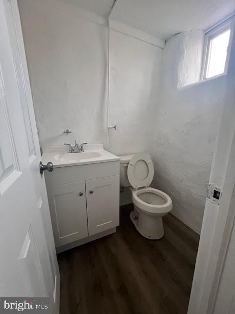 bathroom with toilet, vanity, and hardwood / wood-style flooring