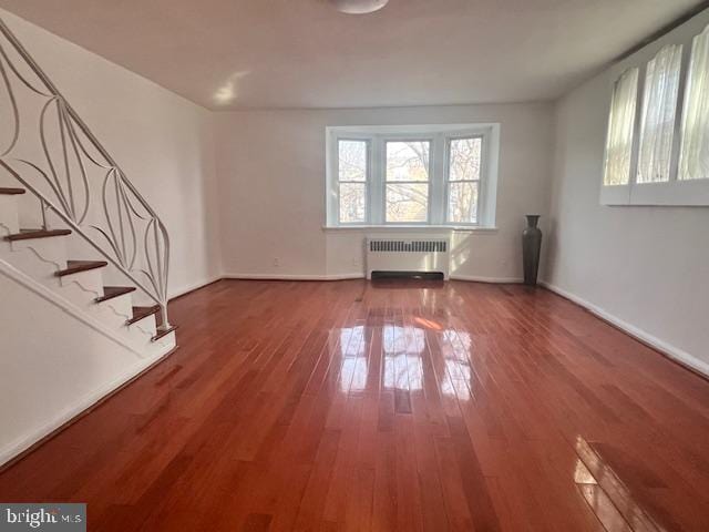 unfurnished living room with hardwood / wood-style floors and radiator heating unit