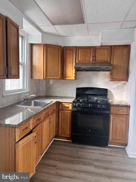 kitchen with a paneled ceiling, sink, stone counters, black gas range, and dark hardwood / wood-style floors