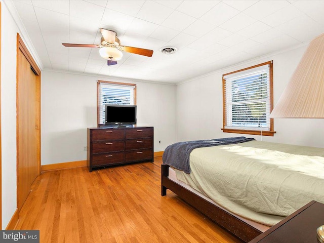 bedroom featuring ceiling fan, a closet, ornamental molding, and light wood-type flooring