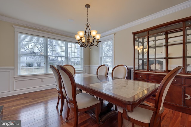 dining space with dark wood-type flooring, an inviting chandelier, and ornamental molding