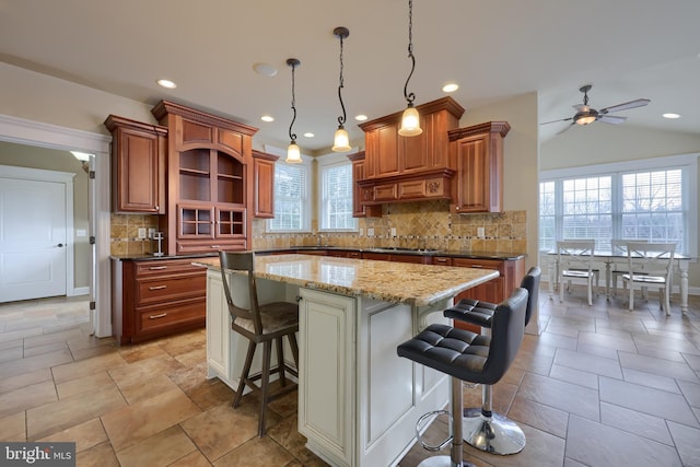 kitchen featuring a kitchen breakfast bar, vaulted ceiling, a healthy amount of sunlight, and a kitchen island