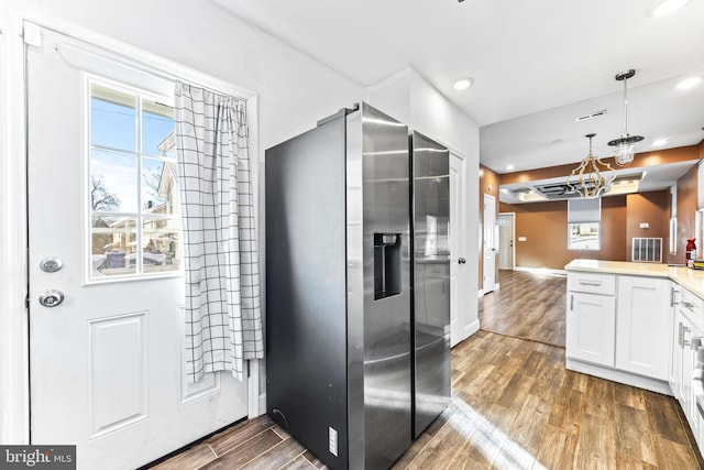 kitchen featuring white cabinetry, dark wood-type flooring, an inviting chandelier, stainless steel fridge, and decorative light fixtures