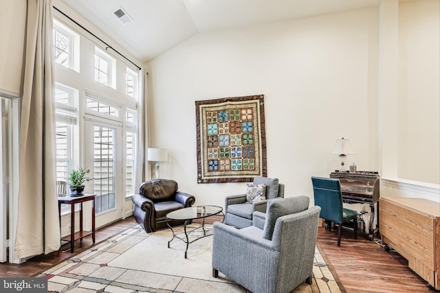 sitting room with wood-type flooring, lofted ceiling, and a healthy amount of sunlight