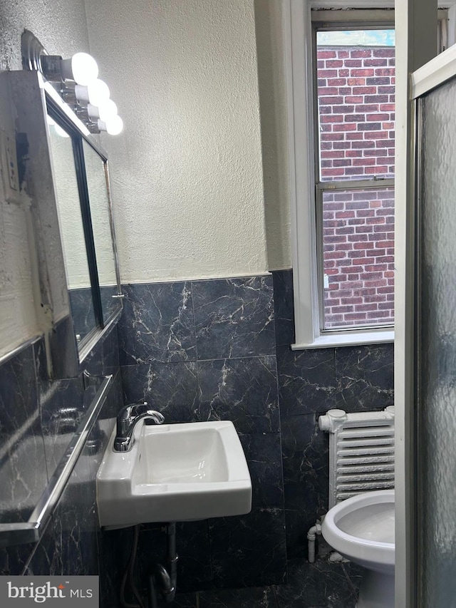 bathroom with sink, tile walls, and toilet