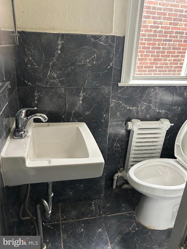 bathroom featuring toilet, tile walls, and sink