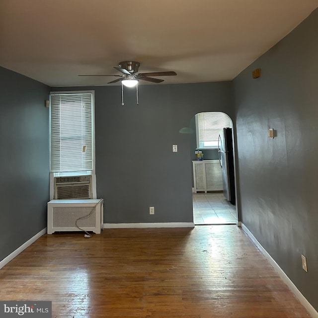 spare room with ceiling fan, cooling unit, radiator heating unit, and light hardwood / wood-style floors