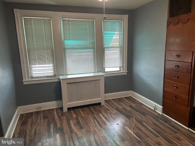 unfurnished dining area with dark wood-type flooring, plenty of natural light, and radiator heating unit