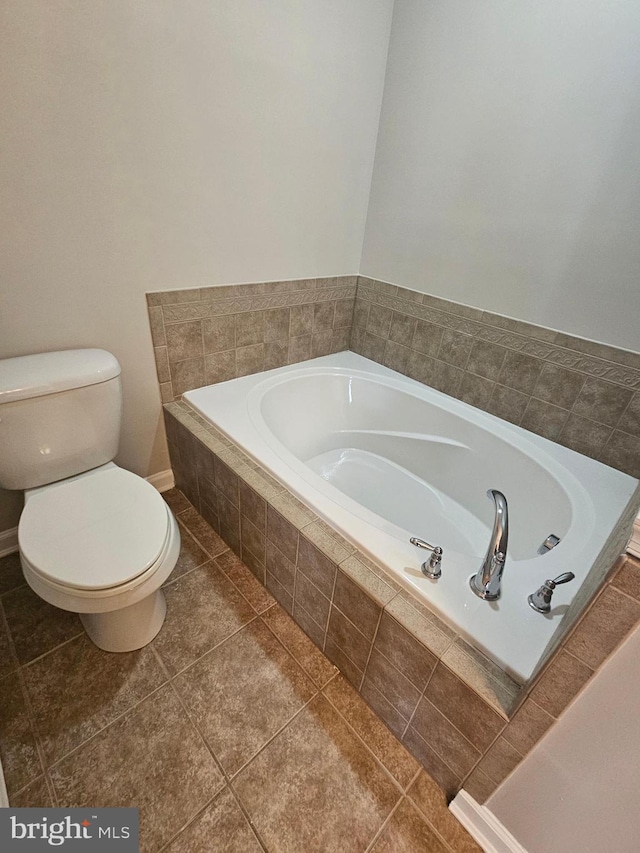 bathroom featuring tile patterned floors, tiled bath, and toilet