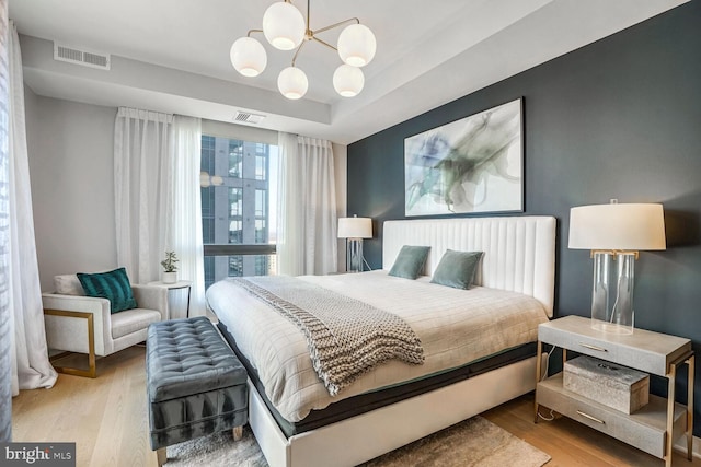 bedroom with light wood-type flooring and an inviting chandelier