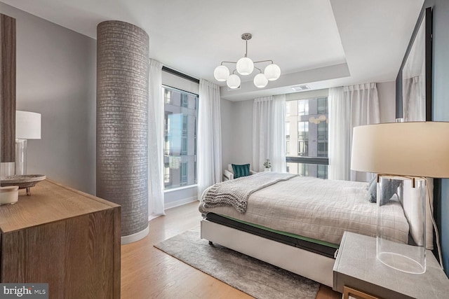 bedroom with a notable chandelier, light hardwood / wood-style floors, and multiple windows