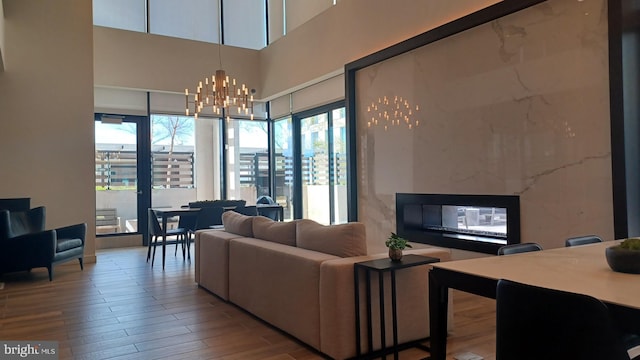 living area with an inviting chandelier, a towering ceiling, and wood finished floors
