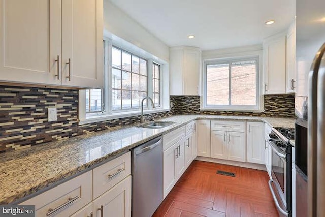 kitchen featuring light stone countertops, white cabinetry, sink, and appliances with stainless steel finishes