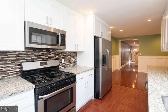 kitchen featuring white cabinets, appliances with stainless steel finishes, backsplash, and light stone countertops