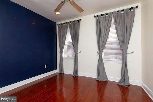 unfurnished room featuring a wealth of natural light, ceiling fan, and dark hardwood / wood-style floors