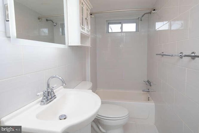 full bathroom with sink, tiled shower / bath combo, tasteful backsplash, toilet, and tile walls