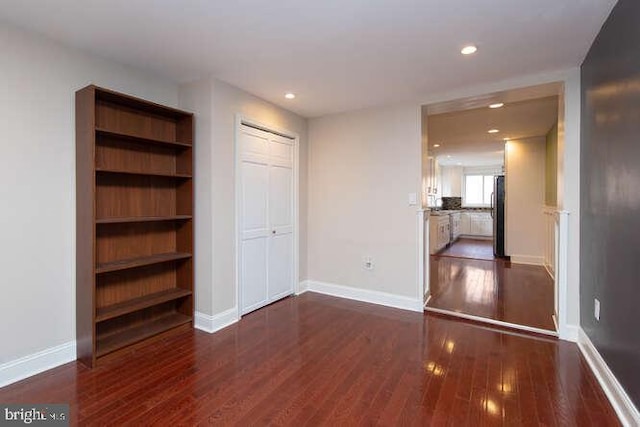 unfurnished bedroom with dark hardwood / wood-style flooring, stainless steel refrigerator, and a closet