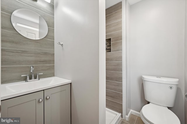 bathroom with walk in shower, vanity, and toilet