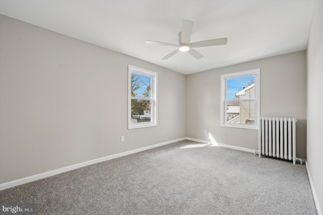 carpeted empty room with radiator heating unit and ceiling fan