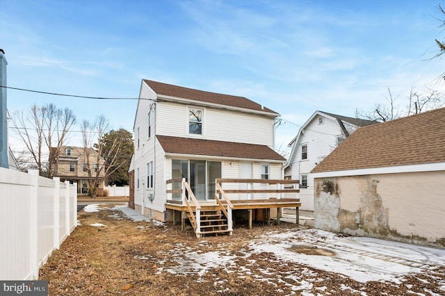 snow covered back of property with a wooden deck