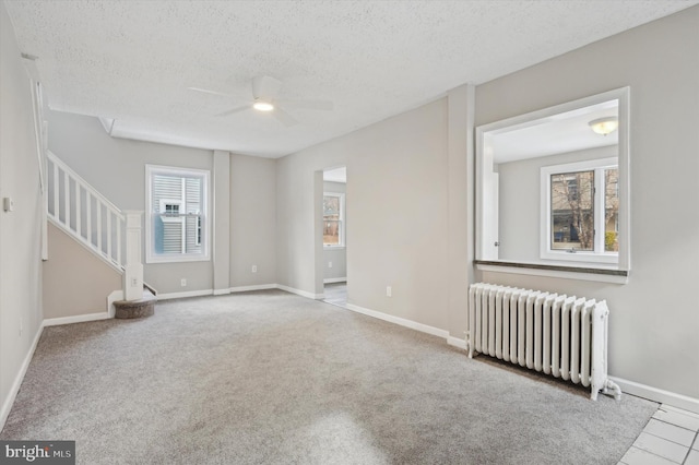 carpeted spare room with a textured ceiling, radiator heating unit, and ceiling fan