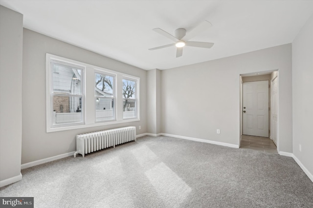 carpeted spare room featuring ceiling fan and radiator