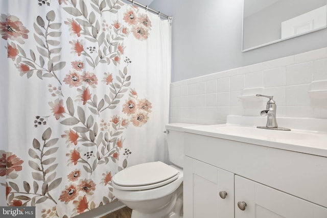 bathroom featuring vanity, tile walls, and toilet