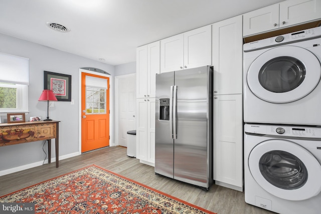 laundry area featuring light hardwood / wood-style floors and stacked washer and clothes dryer