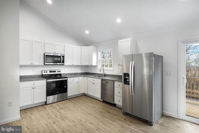 kitchen featuring white cabinets, sink, vaulted ceiling, appliances with stainless steel finishes, and light hardwood / wood-style floors