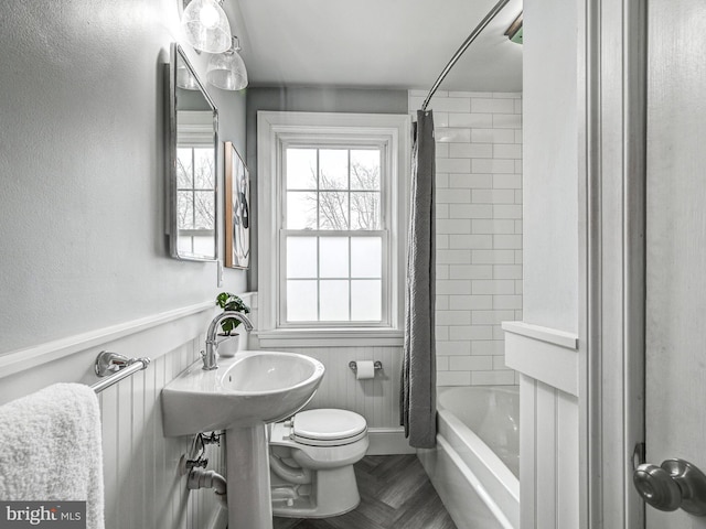 bathroom featuring parquet floors, shower / tub combo, and toilet