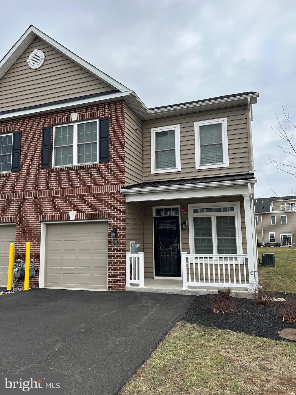 front of property with a porch, a garage, and cooling unit