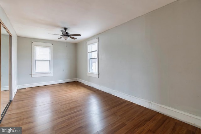 empty room with ceiling fan, a healthy amount of sunlight, and hardwood / wood-style flooring