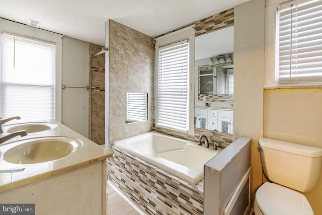 bathroom featuring backsplash, tiled bath, vanity, and toilet