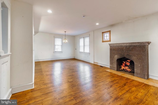 unfurnished living room with hardwood / wood-style floors and a brick fireplace