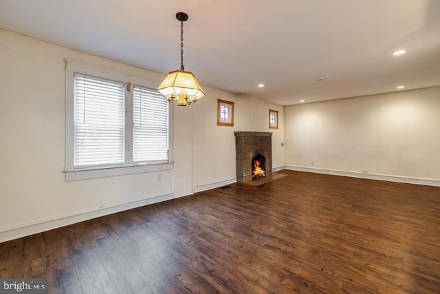 unfurnished living room with dark hardwood / wood-style flooring and a brick fireplace