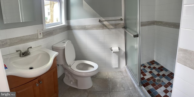 bathroom with a shower with door, vanity, tile walls, and toilet